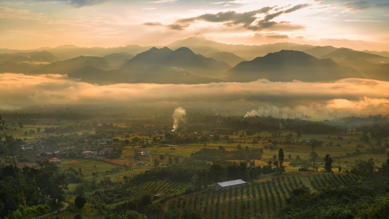 Golden-hour mist over the Pai valley with layered mountain silhouettes